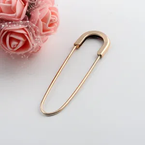 Elegant gold-toned oversized safety pin brooch accessory for sweaters and scarves.