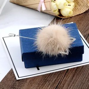 Nahaufnahme einer Nerzpelz-Brosche mit Strassstern auf einer blauen Geschenkbox