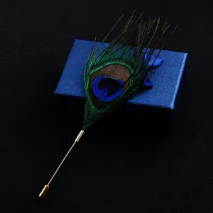 Detailed view of an elegant peacock feather brooch lapel pin on a blue jewelry box.