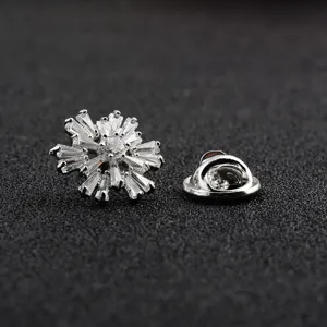 Detail van een zilveren sneeuwvlok reversspeld met zirkonia en vlindersluiting.