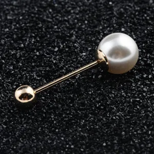 Macro detail of elegant double-headed brooch with large white pearl and polished gold sphere