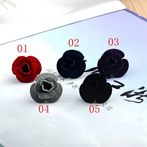 Vue détaillée de cinq épinglettes de rose en velours colorées pour costumes.