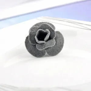 Vue détaillée d'une broche rose en velours gris pour costumes et robes.