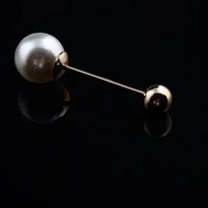 Detailed view of elegant double-headed brooch with large white pearl and gold ball
