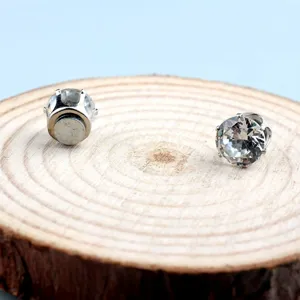 Makroaufnahme magnetischer Zirkonia-Ohrstecker auf einem rustikalen Holzdisplay-Ständer.
