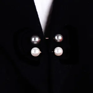 Detailaufnahme von eleganten doppelseitigen Perlenbroschen an einem schwarzen Cardigan