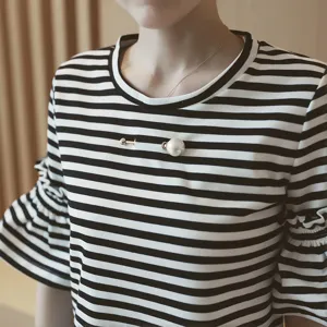 Detailed close-up of an elegant double-headed pearl screw brooch pin on a striped shirt