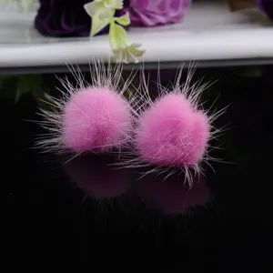 Makroansicht weicher rosa Nerzfell-Ohrringe auf einer schwarzen, glänzenden Fläche