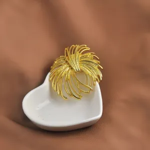 Dettaglio ravvicinato di una spilla a foglia di ginkgo dorata su un piatto a cuore