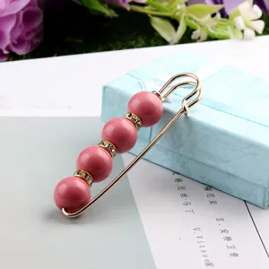 Detail einer eleganten goldene Sicherheitsnadel-Brosche mit rosa Perlen und Kristallen