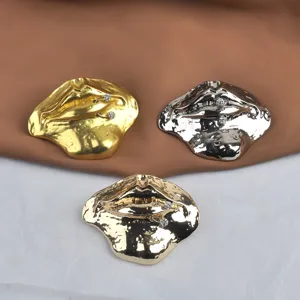 Detailed view of three metallic lip-shaped brooches with molten texture and crystal accents