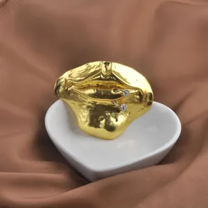 Macro view of a gold 3D lip-shaped brooch with sparkling rhinestone details on satin.