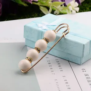 Detailansicht einer eleganten Brosche mit Perlen auf einer hellblauen Geschenkbox