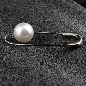 Detailaufnahme einer minimalistischen Sicherheitsnadel-Brosche mit großer Perle.