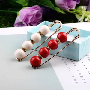 Nahaufnahme von eleganten weißen und roten Perlen-Sicherheitsnadel-Brosche mit Strass