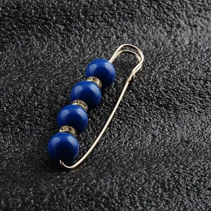 Nahaufnahme einer eleganten goldfarbenen Sicherheitsnadel mit tiefblauen Perlen.
