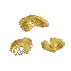 Tre spille vintage in metallo dorato a forma di foglia di ginkgo su sfondo bianco