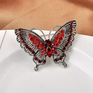 Nahaufnahme einer eleganten Schmetterlingsbrosche mit roten Kristallen und Silbermetall