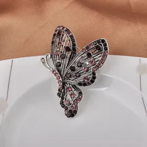 Detailansicht einer Vintage-Schmetterlingsbrosche mit lila Strass auf weißem Teller