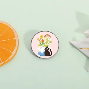 Cute black cat enamel pin with flowers and rainbow on pink background