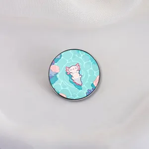 Broche ronde en émail motif axolotl mignon flottant dans une eau vert menthe