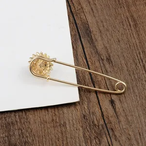 Detail einer goldenen Sicherheitsnadel-Brosche mit dekorativem Sonnenblumen-Design