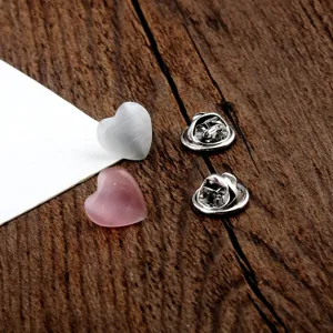 Detailansicht von herzförmigen Katzenaugenstein-Pins mit silbernen Schmetterlingsverschlüssen