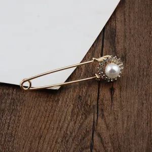 Detailansicht einer eleganten goldenen Sicherheitsnadel-Brosche mit Perle und Strass
