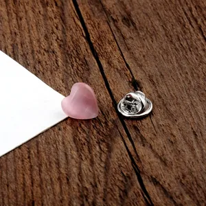 Detailansicht einer rosa herzförmigen Katzenaugenstein-Brosche mit Silberverschluss.