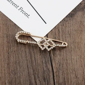 Nahaufnahme einer goldenen geometrischen Sicherheitsnadel-Brosche mit Strass