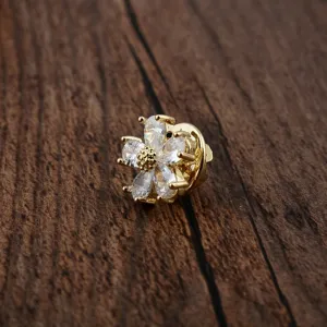 Nahaufnahme einer kleinen goldenen Blumen-Anstecknadel mit Zirkonia-Blütenblättern auf Holz