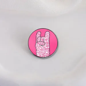 Vibrant pink rock hand gesture metal enamel pin featuring creative hand-drawn doodle patterns