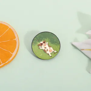Cute cartoon cow with sunglasses lying on green grass illustration badge pin for summer