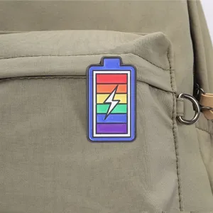 Macro view of a colorful rainbow battery enamel pin badge attached to a green bag