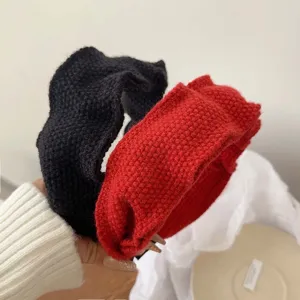 Close-up of hand holding red and black knitted ruffles headbands for a high-top look