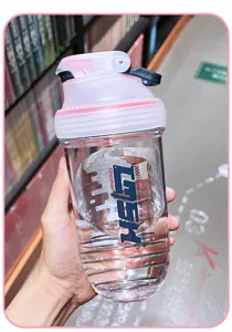 Gourde shaker en plastique transparent avec couvercle rose et boule de mélange pour le sport.