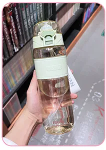 Clear plastic sports water bottle detail view, large capacity with straw and green grip band.