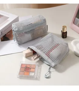 Detailed view of grey mesh cosmetic makeup pouch with zipper and cosmetic items inside.