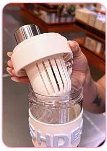 Handheld detail of a heat-resistant fruit tea water bottle with infuser filter and silicone sleeve.