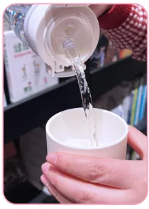 Vista dettagliata della borraccia in plastica con cannuccia in uso, pratico design a doppio becco.