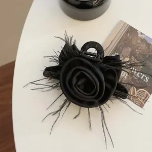 Detail of vintage black rose hair claw clip with delicate feather accents