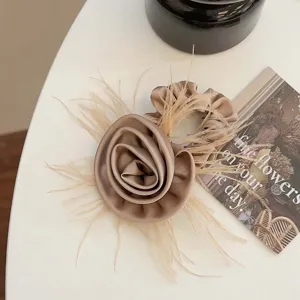 Elegant champagne satin rose hair claw clip with feather detail macro view