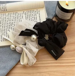 Κοντινό πλάνο από κομψά τούλινα scrunchies με φιόγκο, πέρλα και κορδέλα CHANGE