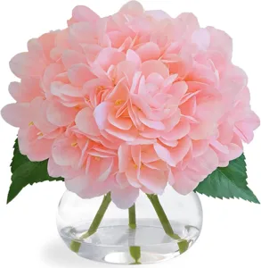 Détail rapproché des fleurs d'hortensias artificielles roses dans un beau vase en verre transparent.