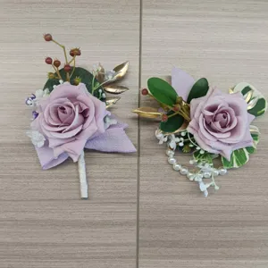Detailed view of artificial wedding flower set, including purple rose boutonniere and wrist corsage.