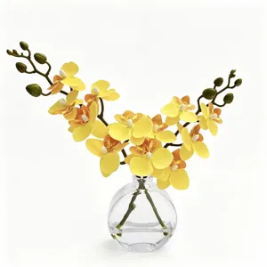 Detail de fleur d'orchidee jaune artificielle en vase en verre transparent avec de l'eau pour deco.