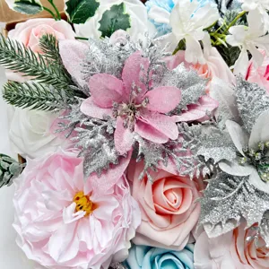 Vue détaillée d'une boîte cadeau de fleurs artificielles roses avec poinsettias et roses.