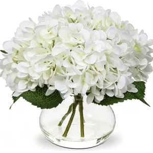 Gros plan détail de fleurs d'hortensia blanches artificielles en vase en verre avec de l'eau imitée