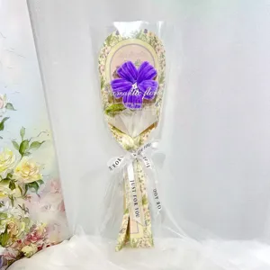 Close-up detail of handmade pipe cleaner purple hibiscus flower bouquet with transparent wrap.
