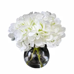 Composition florale d'hortensia blanc artificiel en vase en verre transparent avec de l'eau fausse.